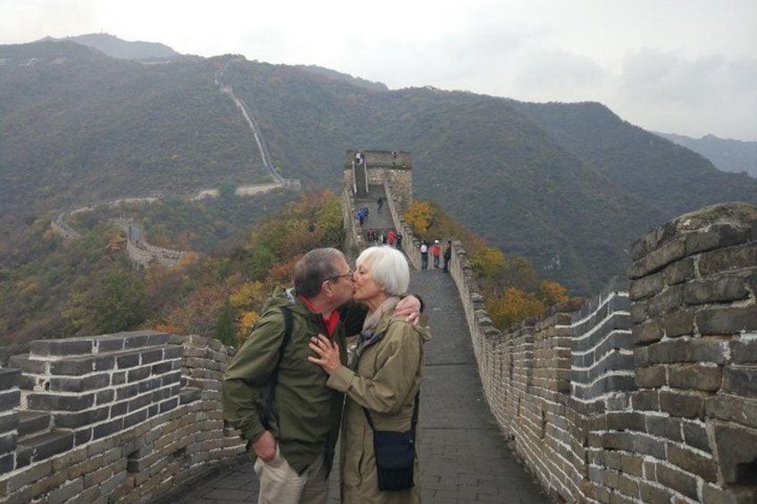 Een stel dat elkaar kust op de Chinese Muur, met bergen op de achtergrond. 2