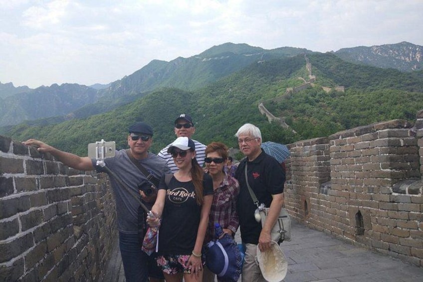 A group of people standing on a wall with a mountainous landscape in the background. 3