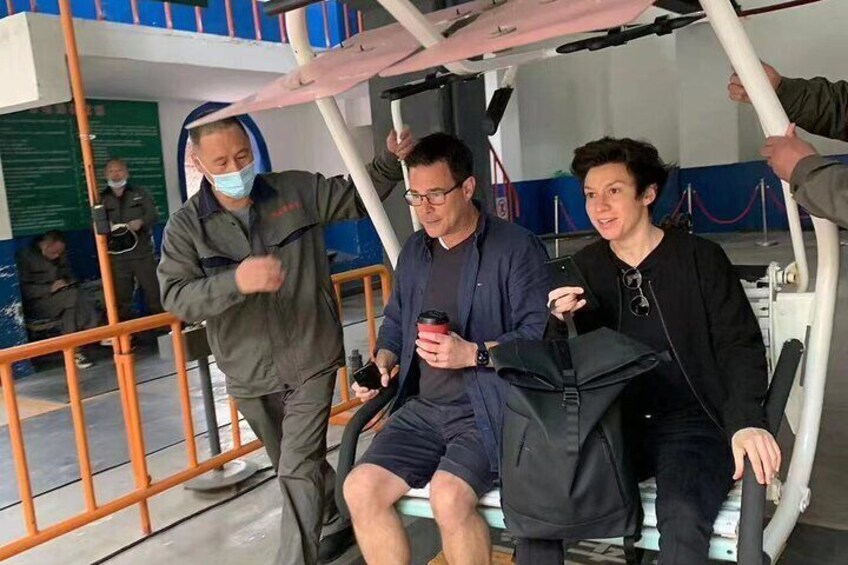 Three people sitting on a bench in an indoor setting with orange railings and a blue wall. 5