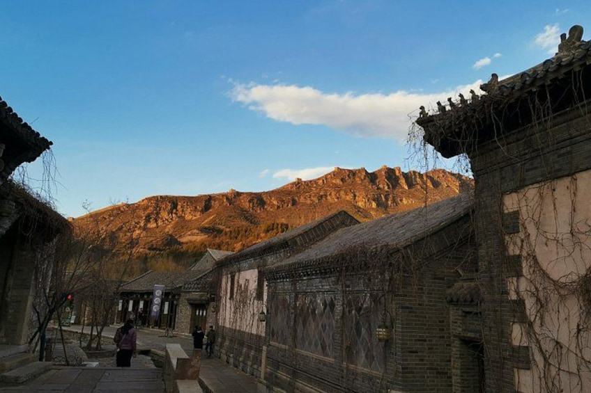 Une rue typique d’un village traditionnel, avec des bâtiments, une montagne en arrière-plan et un ciel dégagé. 2