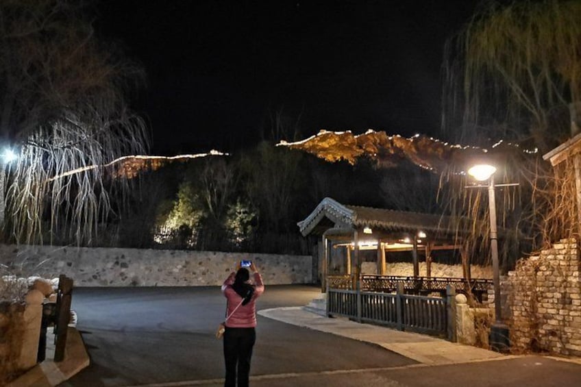 Une personne prenant une photo, un mur de pierre, un bâtiment traditionnel et une montagne en arrière-plan. 3