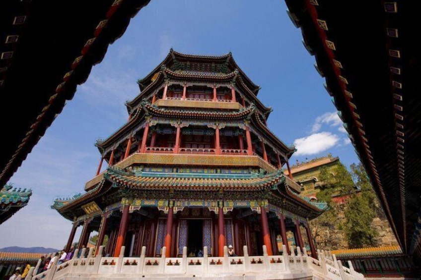 A traditional multi-tiered building with ornate architecture, a clear blue sky, and a white fence in the foreground. 1