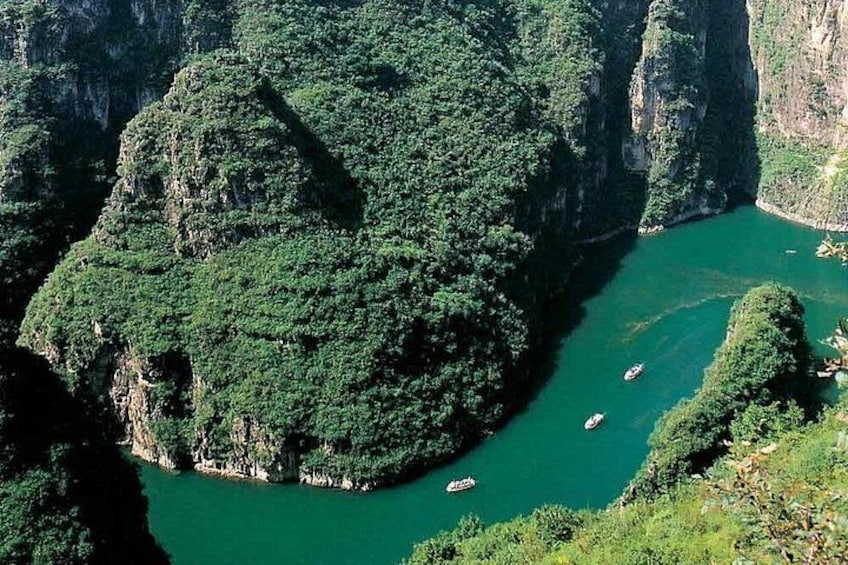 A river surrounded by steep cliffs, boats on the water, and dense greenery. 1