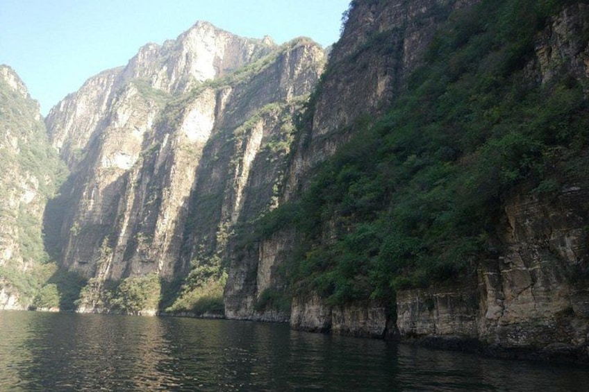 A river with steep, rocky cliffs and dense green vegetation. 3