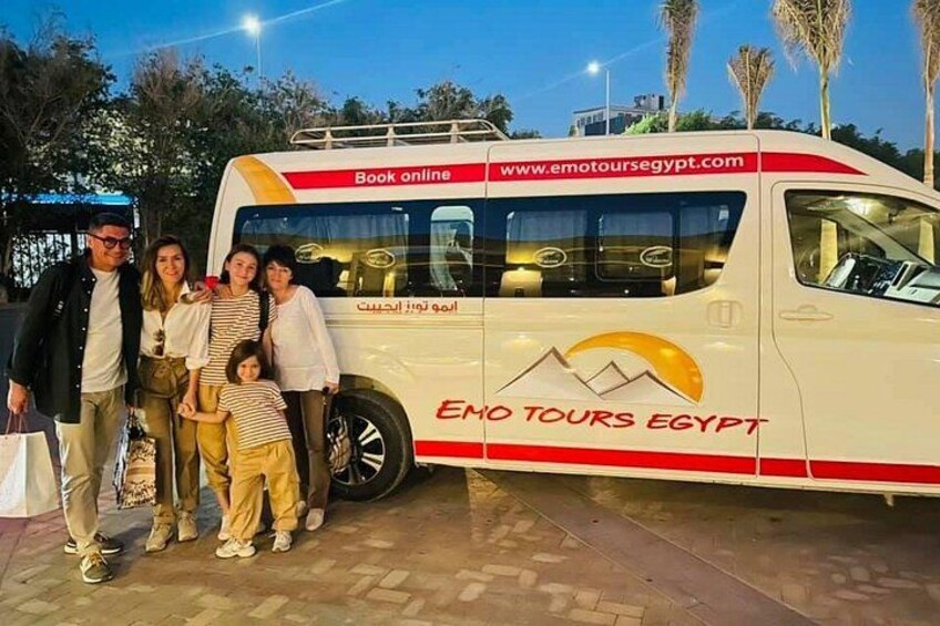 Une famille pose devant un autocar de tourisme arborant le logo « Emo Tours Egypt ». 2