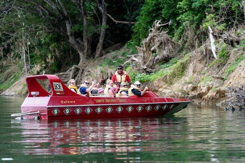 Un bateau rouge, transportant des passagers, navigue sur une rivière bordée d’arbres. 2