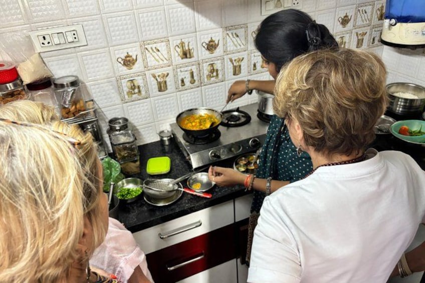 Una cocina con estufa, ollas y una persona cocinando. 5