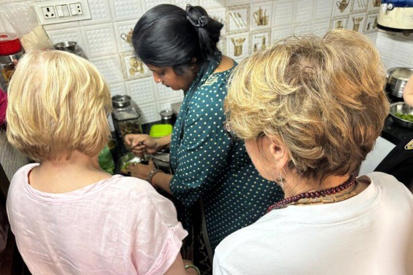 Un grupo de personas en una cocina, algunas preparando comida. 3