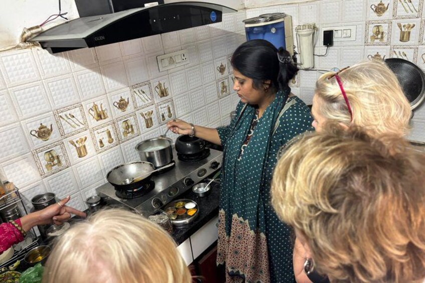 Una cocina con estufa, ollas y una persona cocinando. Hay azulejos decorativos en la pared. 1