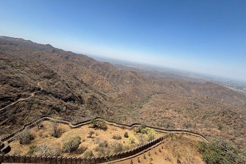 Eine Berglandschaft mit einer kurvenreichen Straße und einer Steinmauer. 2