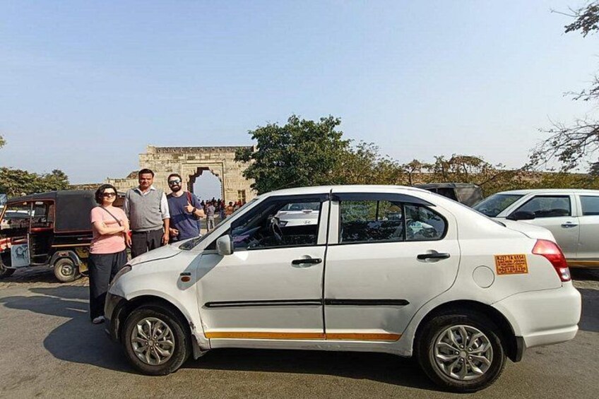 Un coche blanco estacionado en un estacionamiento, con un grupo de personas de pie a su lado. 2