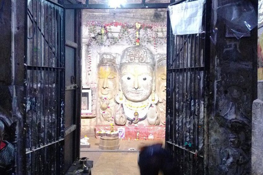 Una entrada de templo con dos estatuas grandes, un portón y un pequeño altar. 3