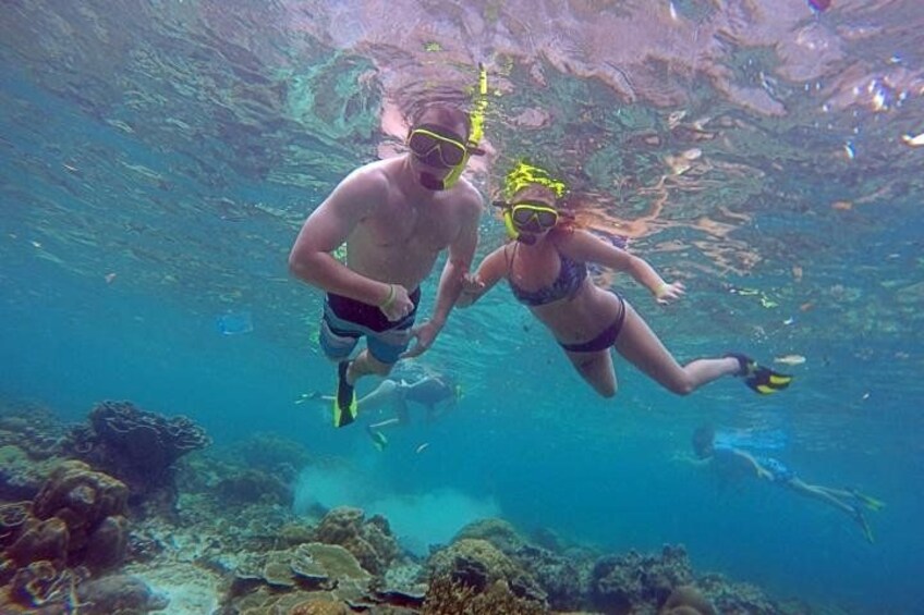 Deux personnes pratiquent la plongée avec tuba sous l’eau, avec des récifs coralliens et une faune marine en arrière-plan. 4