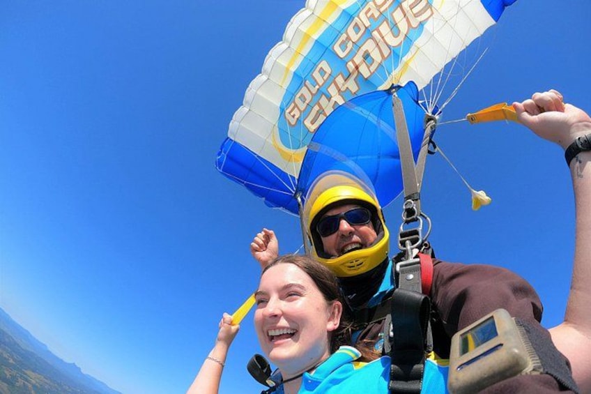 A person skydiving with a parachute, wearing a helmet and harness. 2