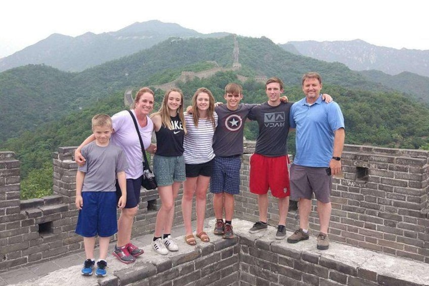 A group of people standing on a wall with a mountainous landscape in the background. 2