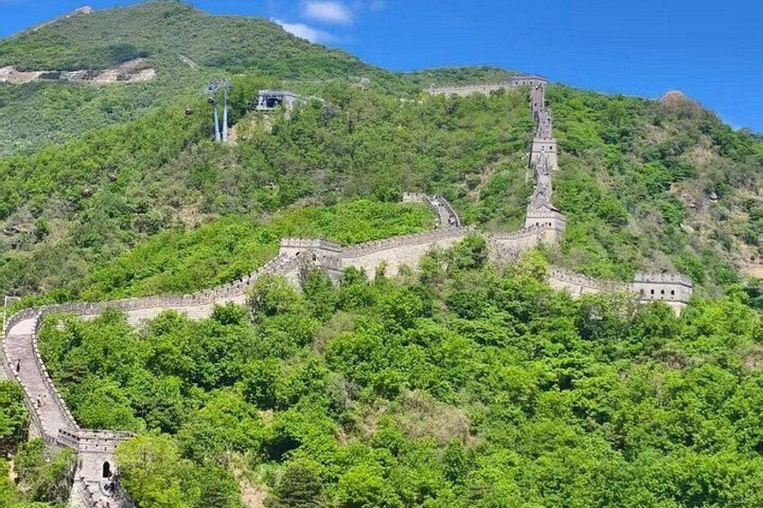 A section of the Great Wall of China winding through a lush green landscape. 4