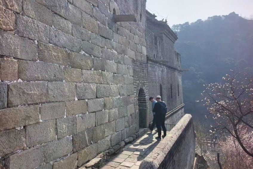 A stone wall with a narrow pathway and a view of a mountainous landscape. 5