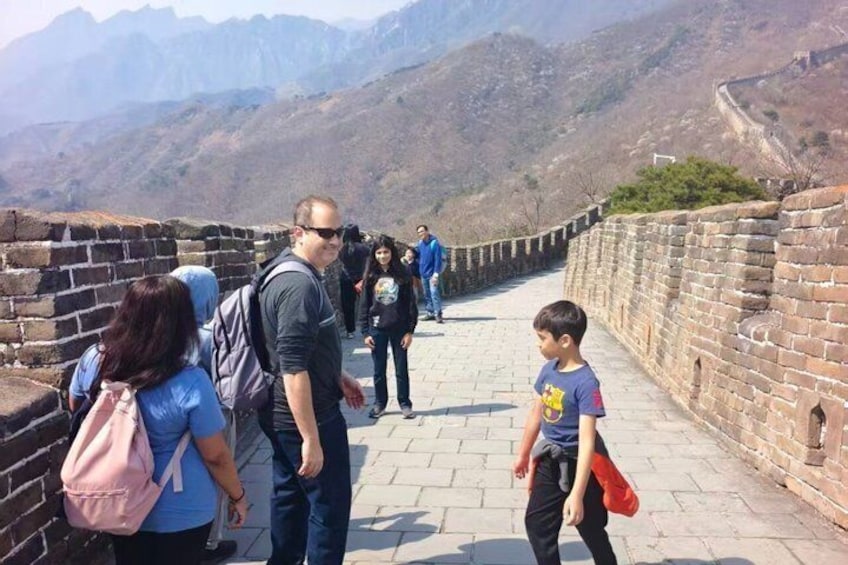 A group of people walking on the Great Wall of China, with mountains in the background. 3