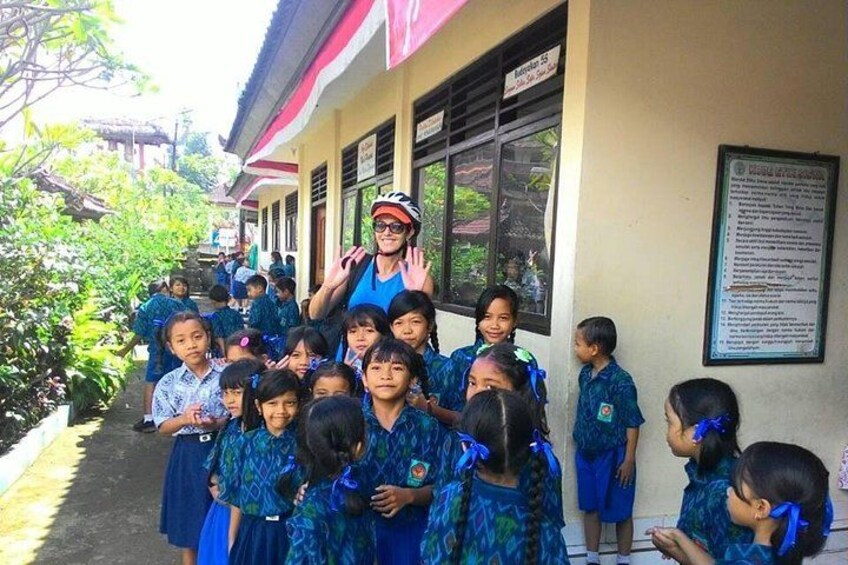 Een groep kinderen in blauwe uniformen staat voor een schoolgebouw. 2