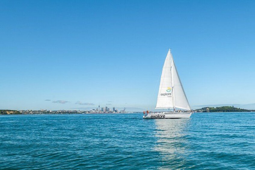 A sailboat with 'explore' written on its sail, sailing on a body of water with a city skyline in the background. 4