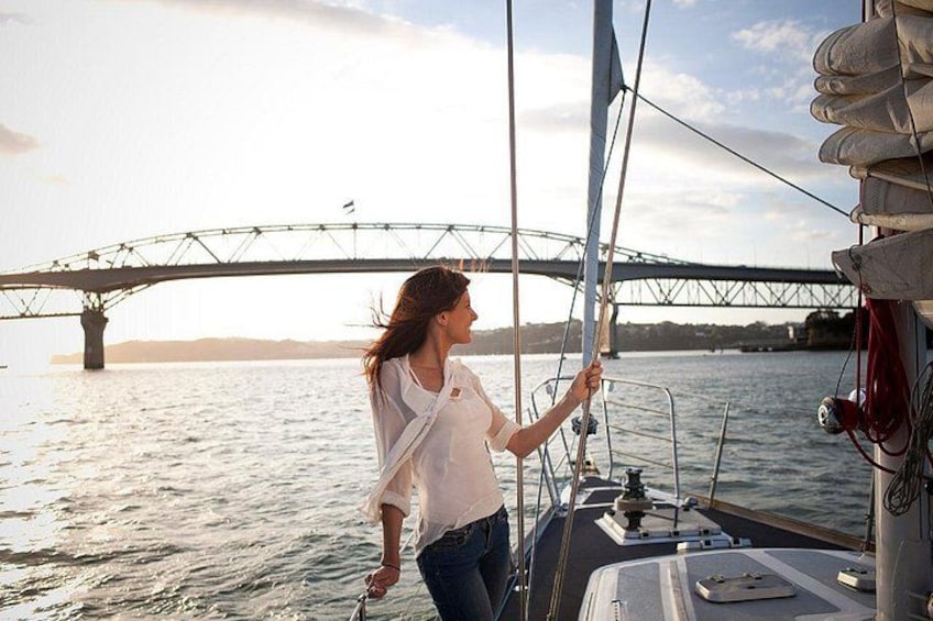 A person on a sailboat with a bridge in the background. 1