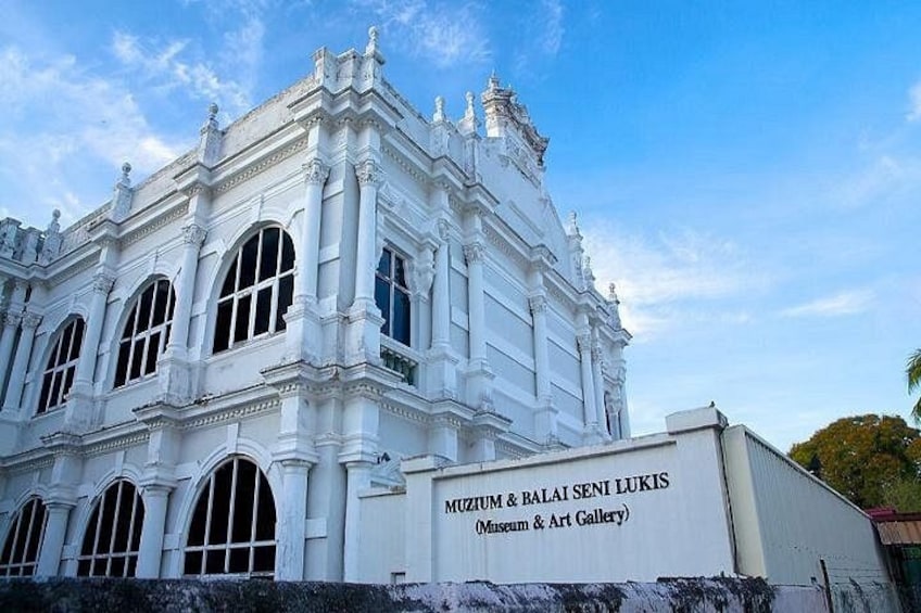 Un edificio de estilo colonial blanco con ventanas arqueadas y un letrero que dice 'MIZUMI & BALAI SENI LUKIS Museum & Art Gallery'. 1