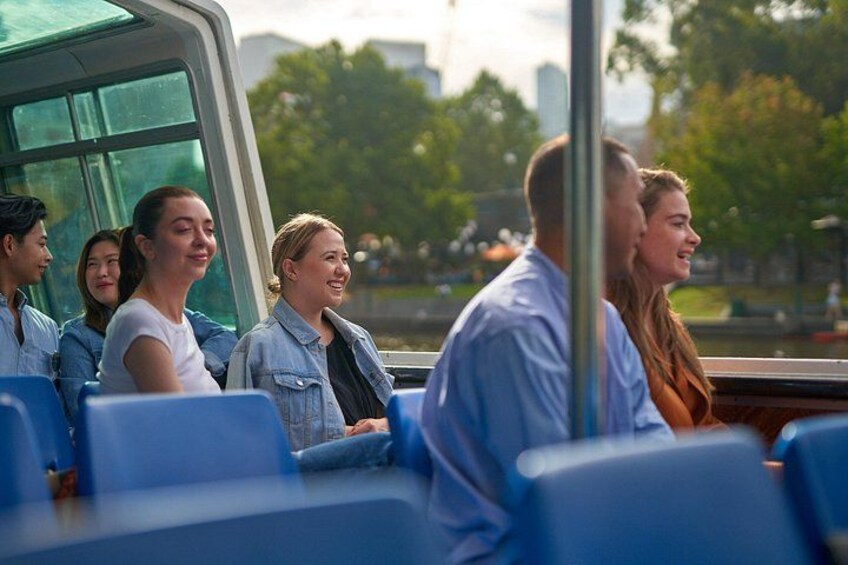 Des passagers sont assis dans un autobus, et les fenêtres offrent une vue sur les arbres et les bâtiments. 5