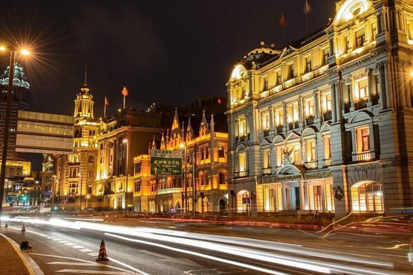 A brightly lit historic building with ornate architecture, a street with light trails from moving vehicles, and a clear night sky. 3