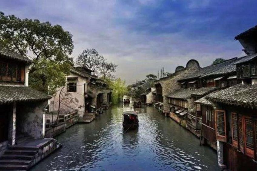 A narrow waterway flanked by traditional buildings with tiled roofs and wooden structures. 1