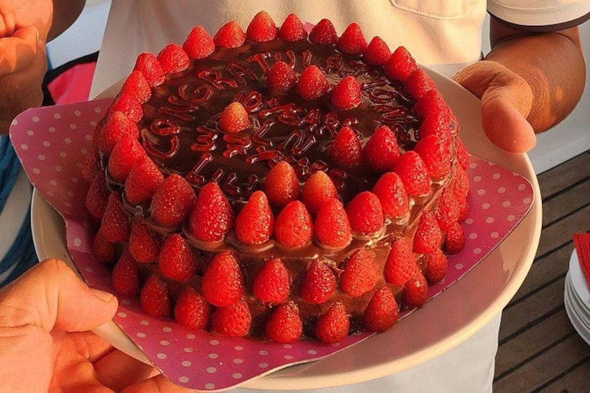 Un pastel con fresas por encima, sostenido por una persona. 3