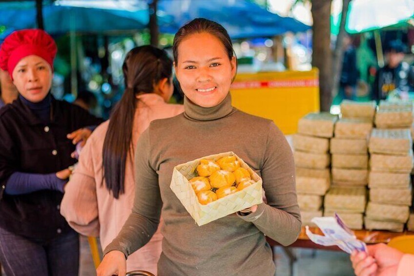 A person holding a box of food items at a market. 5
