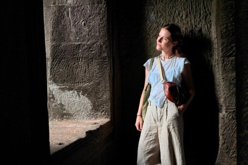 A person standing in a stone structure with a window. 4