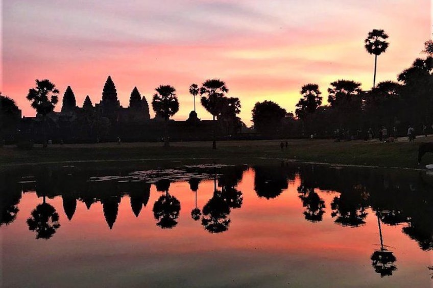 A sunset over a calm lake with reflections of trees and a temple silhouette. 3