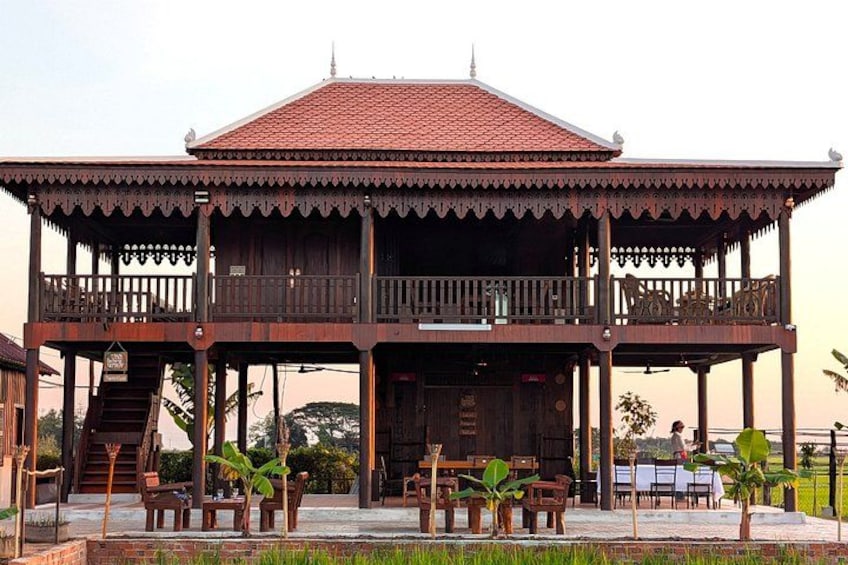 A wooden pavilion with a tiled roof, surrounded by a garden with potted plants and a staircase leading to an upper level. 4