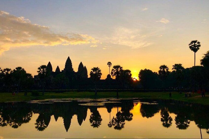 A sunset with a reflection of a temple complex in a body of water. 2
