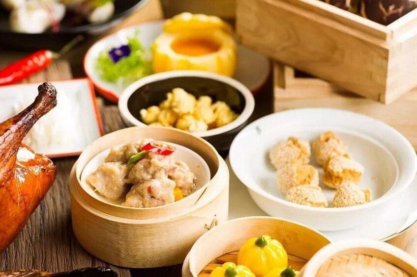Diverse gerechten, waaronder dumplings, een gebraden kokerret en andere etenswaren op een houten tafel. 2