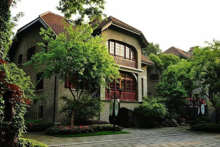 A traditional building with a red balcony, surrounded by lush greenery and a paved courtyard. 3