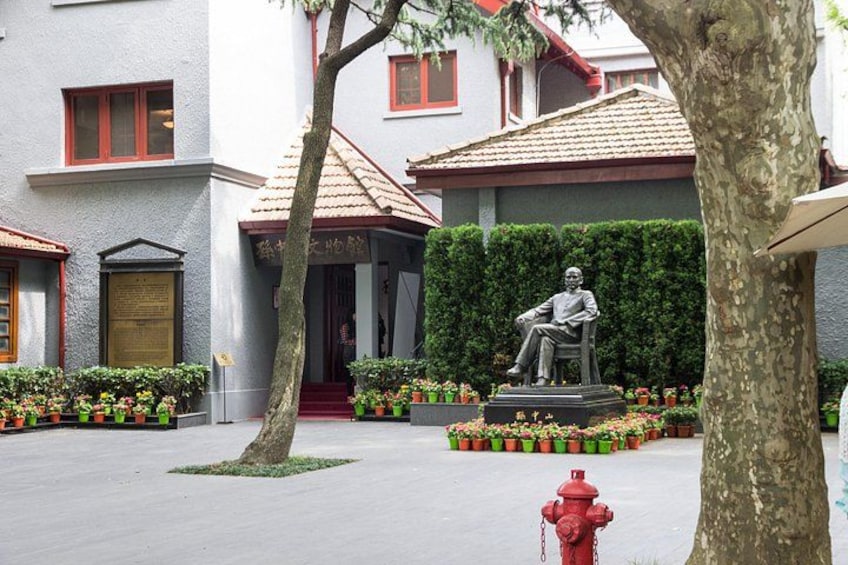 A courtyard with a statue, a red fire hydrant, and a building with a red roof. 4