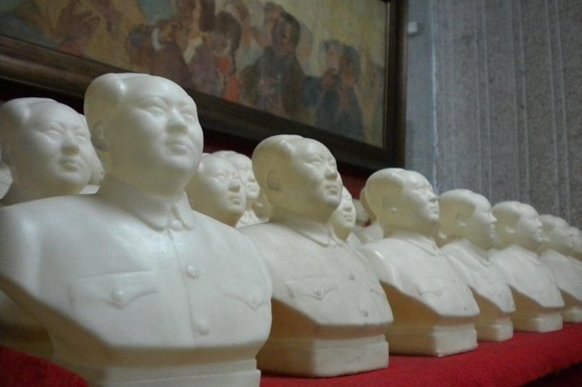 A row of white bust sculptures on a red surface. 1