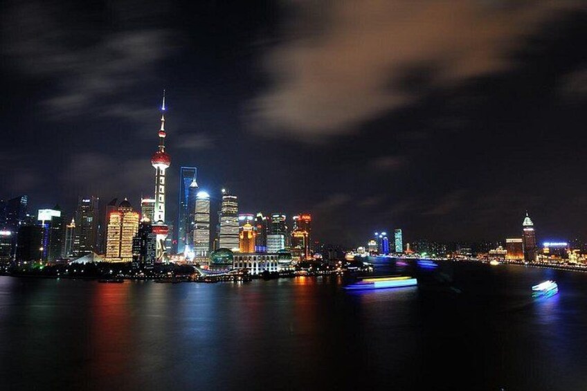 Eine beleuchtete Stadtlandschaft bei Nacht mit Gebäuden und einem markanten Turm. 4