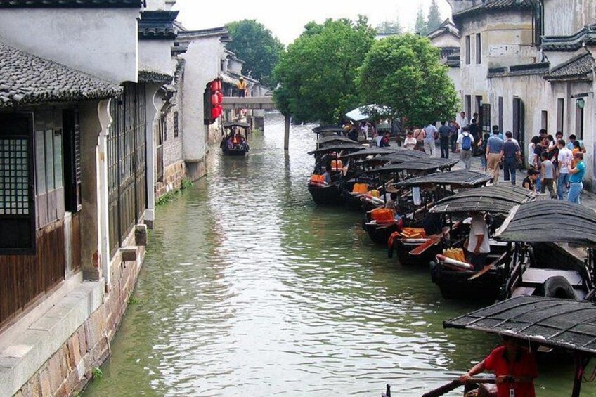 Un canal estrecho bordeado por edificios tradicionales, un puente y varias embarcaciones amarradas a un lado. 2