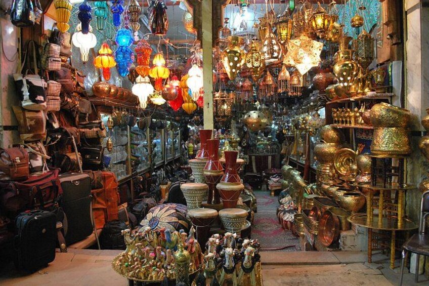 A crowded market with various stalls selling bags, lanterns, and pottery. 2