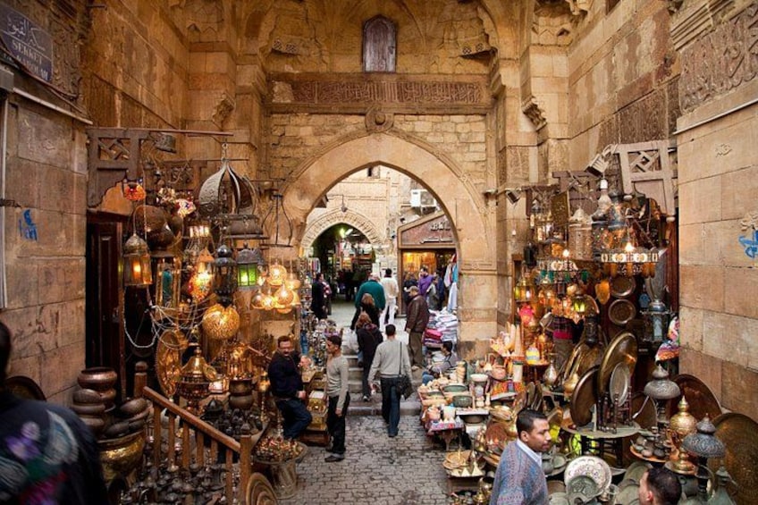 An indoor market with stone arches, various stalls selling pottery, and hanging lanterns. 3