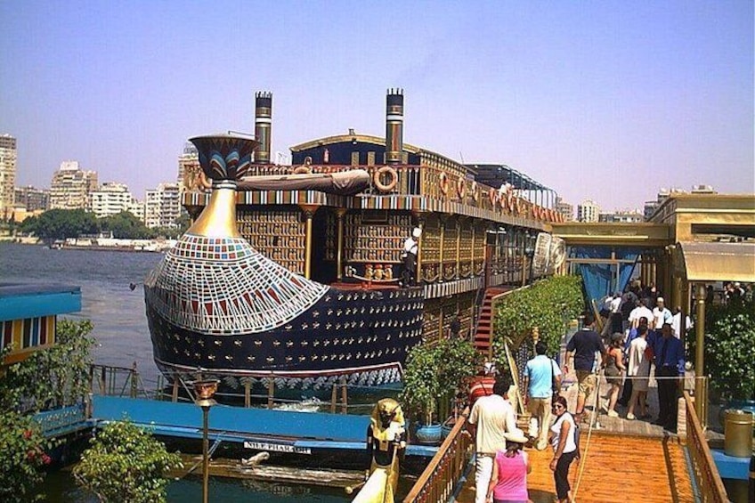 A large, ornate boat docked at a pier with people walking around it. 3