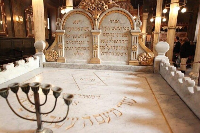 A synagogue interior with ornate decorations, a menorah, and Hebrew inscriptions on the walls. 2