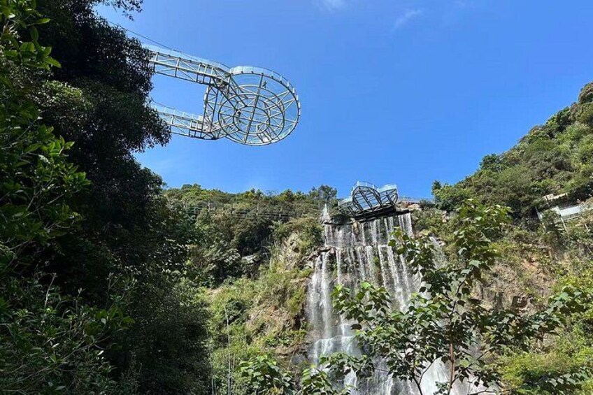 A waterfall, a metal structure, and dense greenery. 2