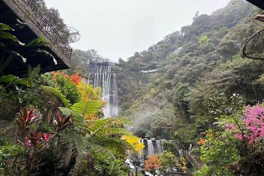 A waterfall cascading down a hillside, surrounded by lush greenery and a bridge. 5