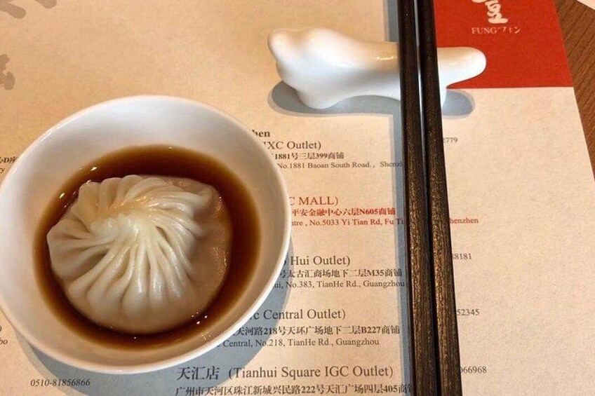 A bowl of dumplings in soup with chopsticks and a menu. 1