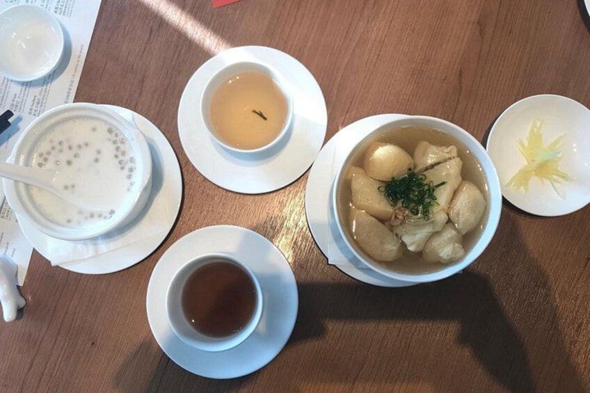 A wooden table with various dishes including a bowl of soup, a bowl of rice, and a cup of tea. 3