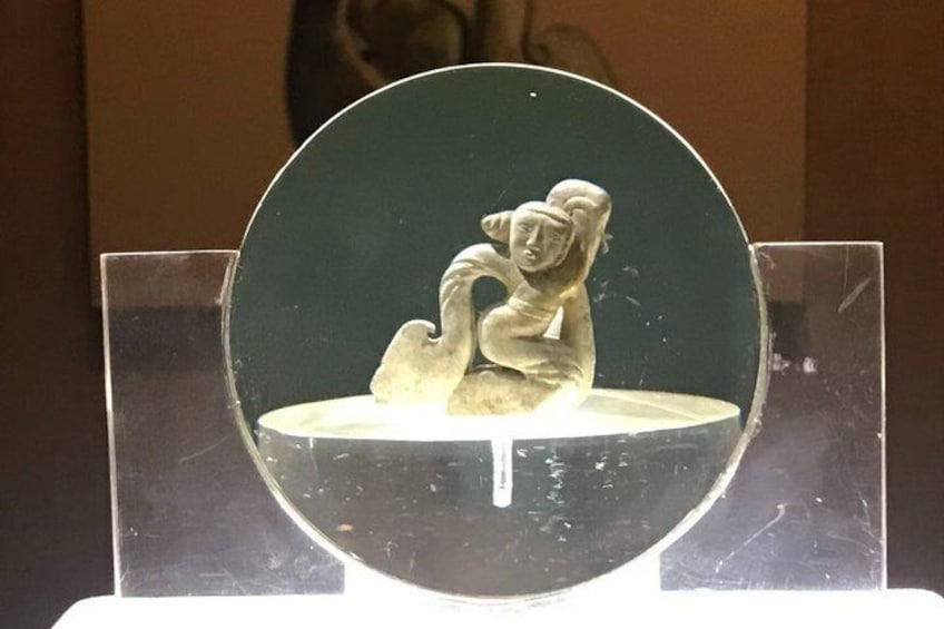 En skulptur af en siddende figur på en sokkel. 4